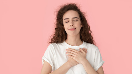 Grateful woman touch heart with hands isolated on pink background