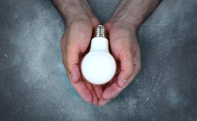 Concept of hope with lighting bulb in strong brutal male hands.