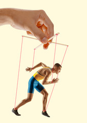 Man like a puppet in somebodies hands on yellow background. Concept of unfair manipulation,...