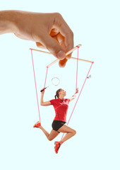 Woman like a puppet in somebodies hands on blue background. Concept of unfair manipulation,...