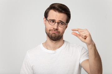 Headshot portrait guy in glasses showing with fingers something small