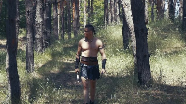 Slow motion footage of a big barbarian with two axes in the forest