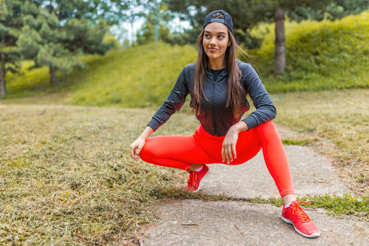 Young woman posing in fitness outfit. Portrait of young sports woman relaxing outdoors after workout.  Female jogger in bright sportswear smiling looking away, advertising for sports