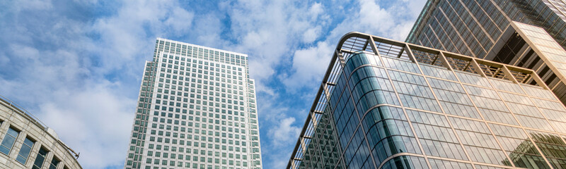 Fototapeta premium Modern city building architecture with glass fronts on a clear day in London, England at sunrise panoramic