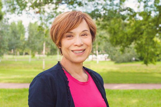 Closeup Portrait Of Healthy Smiling Older Woman Outdoors. Elegant Mature Redhead Woman With Short Hair Smiling