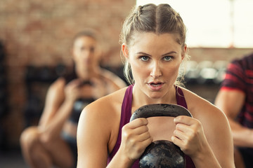 Determined fitness woman doing squat with kettle bell