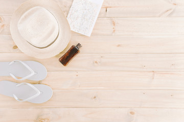 Hat; map; flip flops and bottle on wooden plank background