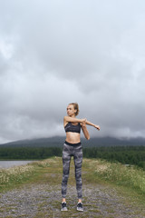 Skinny woman stretching outdoors on rainy day