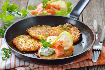 Resche Kartoffelpuffer mit Räucherlachs und Kräuter-Creme-Fraiche in der Eisenpfanne serviert –...