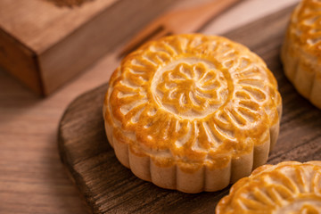 Round shaped moon cake Mooncake - Chinese style traditional pastry during Mid-Autumn Festival / Moon Festival on wooden background and tray, close up