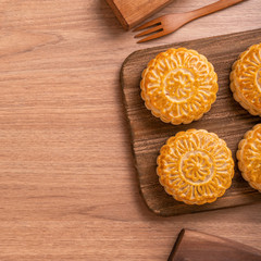 Fototapeta na wymiar Round shaped moon cake Mooncake - Chinese style pastry during Mid-Autumn Festival / Moon Festival on wooden background and tray, top view, flat lay.