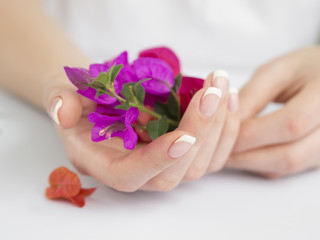 Obraz na płótnie Canvas Delicate manicured hands holding flowers