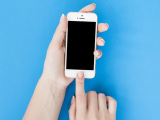 Woman hands holding smartphone on blue background