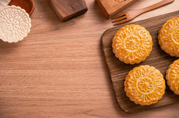 Round shaped moon cake Mooncake - Chinese style pastry during Mid-Autumn Festival / Moon Festival on wooden background and tray, top view, flat lay.