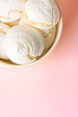 Home baked meringue cookies in white bowl on light pink background. French Italian Swiss cuisine confection coffee dessert recipe poster cafe menu