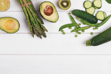 Green colored vegetables and fruits on the white wooden background