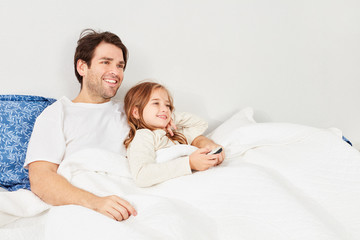 Vater und Tochter schauen Fernsehen im Bett