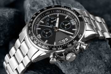 men's wrist watch made of white metal on the background of stones, chrome wrist watch