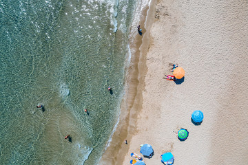 Aerial view of beautiful sandy beach with umbrellas and sunbeds and chairs. Relax on the beach. Sandy seashore place for rest.