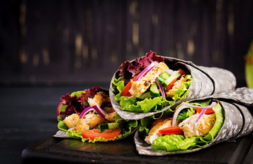 Tortilla with added ink cuttlefish wraps with chicken and vegetables on black background. Chicken...