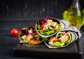 Tortilla with added ink cuttlefish wraps with chicken and vegetables on black background. Chicken...