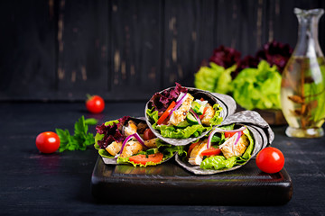 Tortilla with added ink cuttlefish wraps with chicken and vegetables on black background. Chicken...
