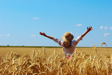 Happy young girl walking on a wheat meadow. People, nature, travel concept.