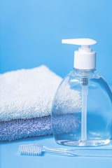 Obraz na płótnie Canvas Liquid transparent eco friendly soap bottle and two towels on blue background with toothbrush. Hygiene and bathroom with copy space