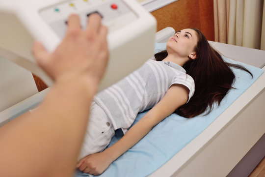 young pretty girl on examination in a modern clinic by densitometry - checking the density of bone tissue.