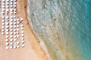Aerial view of beautiful sandy beach with umbrellas and sunbeds and chairs. Relax on the beach. Sandy seashore place for rest.