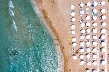 Aerial view of beautiful sandy beach with umbrellas and sunbeds and chairs. Relax on the beach. Sandy seashore place for rest.