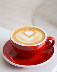 Cappuccino mit Latte Art auf einem weißen Tisch