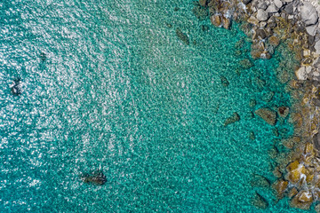 Aerial view of the ocean and rocks and stones. Beautiful sunny coast  seen from above.