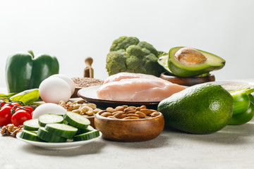 fresh raw chicken breasts near green vegetables and nuts isolated on grey, ketogenic diet menu