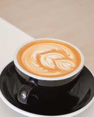 Cappuccino mit Latte Art auf einem weißen Tisch