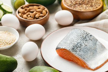 fresh salmon on white plate near nuts and eggs, ketogenic diet menu