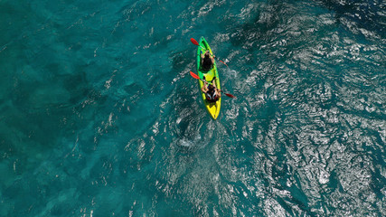 Aerial drone photo of fit couple practising on a colourful canoe in turquoise open ocean bay with crystal clear sea