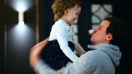 The father puts fake moustache and lifts his little daughter up