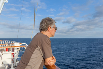 Fototapeta premium Man looking at the horizon of the sea from the deck of a cruise ship