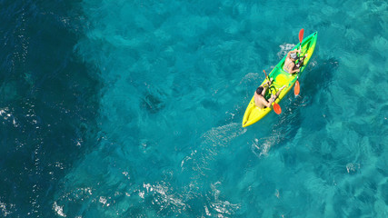 Aerial drone photo of fit couple practising on a colourful canoe in turquoise open ocean bay with crystal clear sea