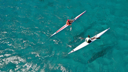 Aerial photo of fit athletes competing on sport canoe in tropical exotic bay with crystal clear turquoise sea
