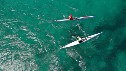 Aerial photo of fit athletes competing on sport canoe in tropical exotic bay with crystal clear...