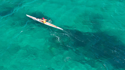 Aerial photo of fit athletes competing on sport canoe in tropical exotic bay with crystal clear turquoise sea