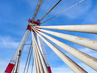 Architecture of cable-stayed bridge with many steel cables connected to top of high red and white tower.