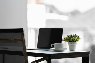 Working table with laptop, coffee cup, flowers vase.
