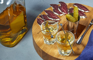 whiskey in two glasses and sliced jerky with spices on the oak surface