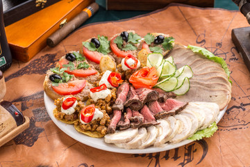 Different appetizer and smoked meat on the plate on old map background