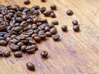 Heap of coffee grains on wooden table, macro