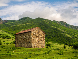 Georgian landscape with Orthodox chapel standing on a green hillside