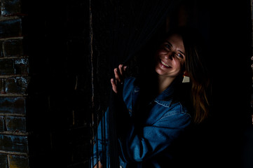 brunette girl in a green jacket and bra stands near the white brick wall.